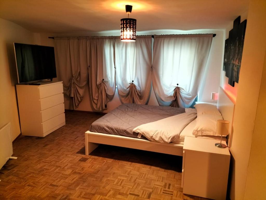 1 dormitorio con 1 cama, TV y cortinas en Red appartament, en Bagnolo Piemonte