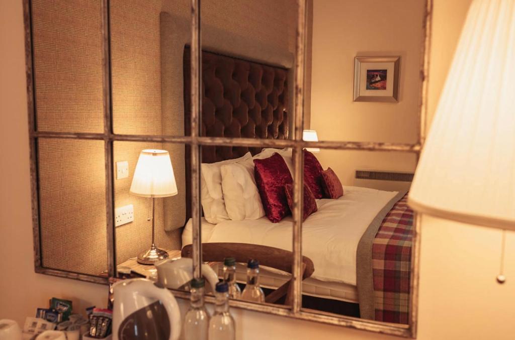 a reflection of a bedroom with a bed in a mirror at The Bowmore Lodge in Bowmore