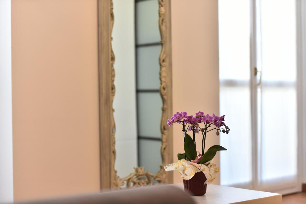 a vase with purple flowers on a table in front of a mirror at PONTACCIO22 APARTMENT- BRERA CENTRO STORICO in Milan