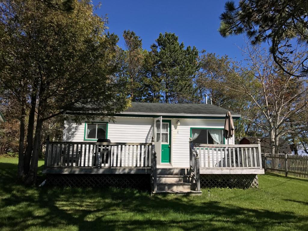 una piccola casa bianca con portico e recinzione di By the Bay Cottages a Stanhope