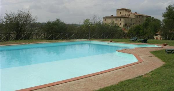 a large blue swimming pool with a building in the background at Residenza Il Platano Fortilizio di Campiglia in Rapolano Terme