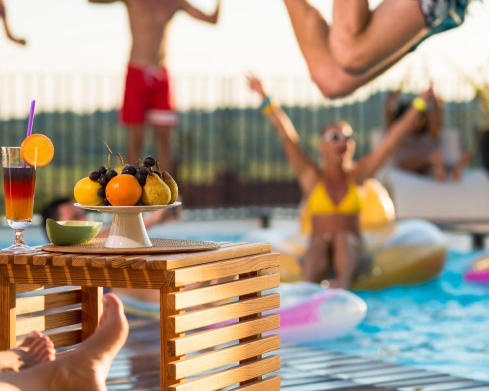 a group of people in a swimming pool with a bowl of fruit at Topazio Vibe Beach Hotel & Apartments - Adults Friendly in Albufeira