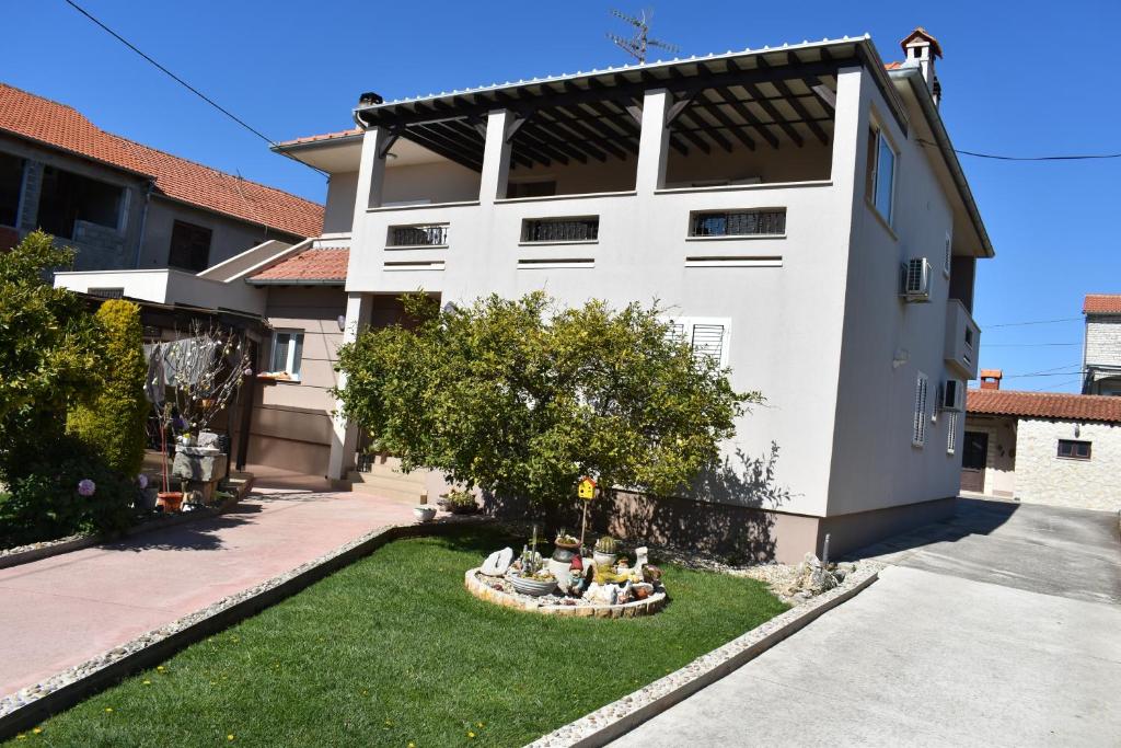 a white house with a garden in front of it at Apartman DODO in Zadar