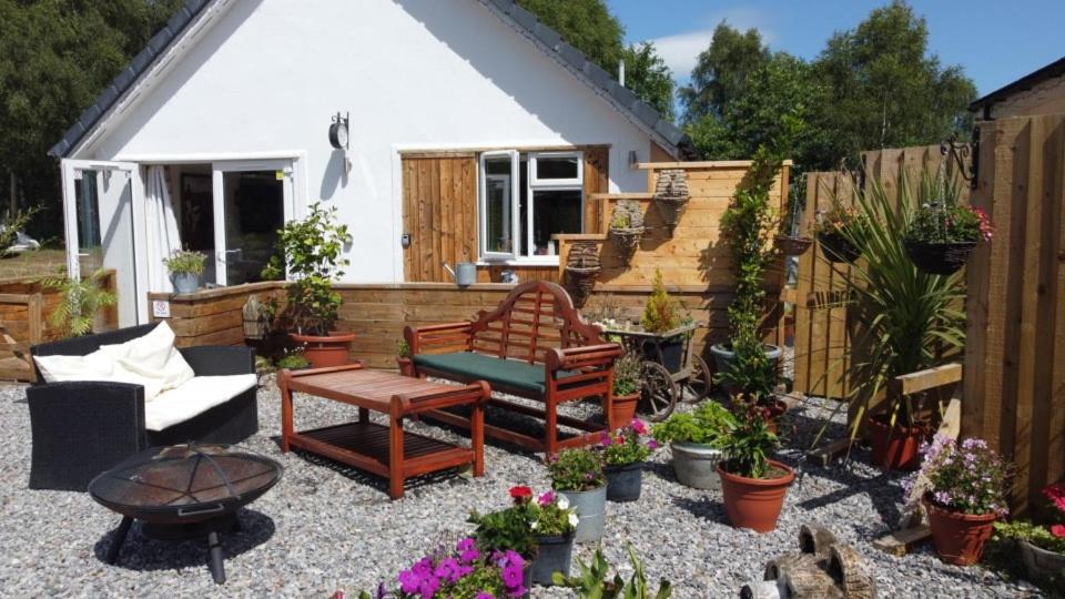 a patio with furniture and plants in front of a house at Highland Retreats Cannich in Cannich