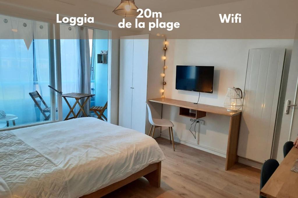 Un dormitorio con una cama y un escritorio con televisión. en Le levant - avec loggia - à 20m de la plage, en Courseulles-sur-Mer