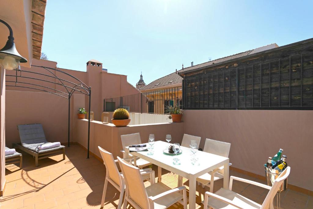 eine Terrasse mit einem weißen Tisch und Stühlen auf dem Balkon in der Unterkunft La Mansión de Compañia ApartamentosMalagaManagement in Málaga