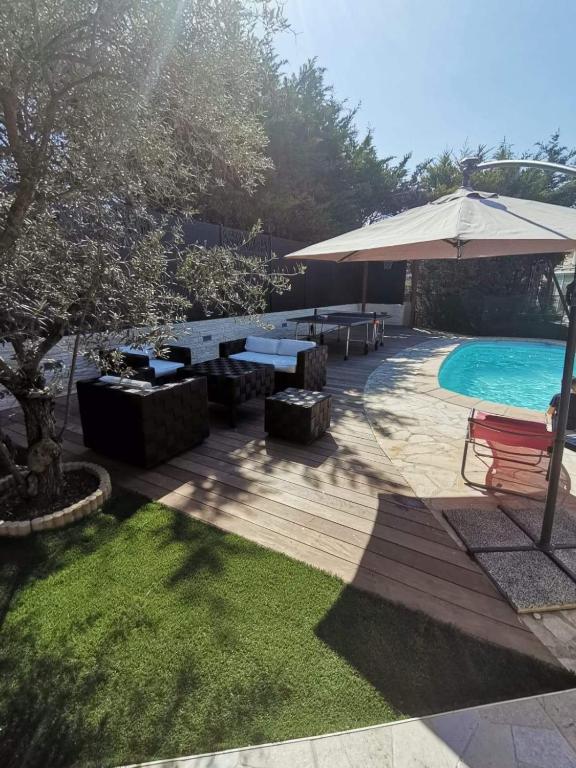 une cour avec une piscine et un parasol dans l'établissement Villa Jasmin, bas de villa, à 10 min de Cannes, piscine privée chauffée, au Cannet