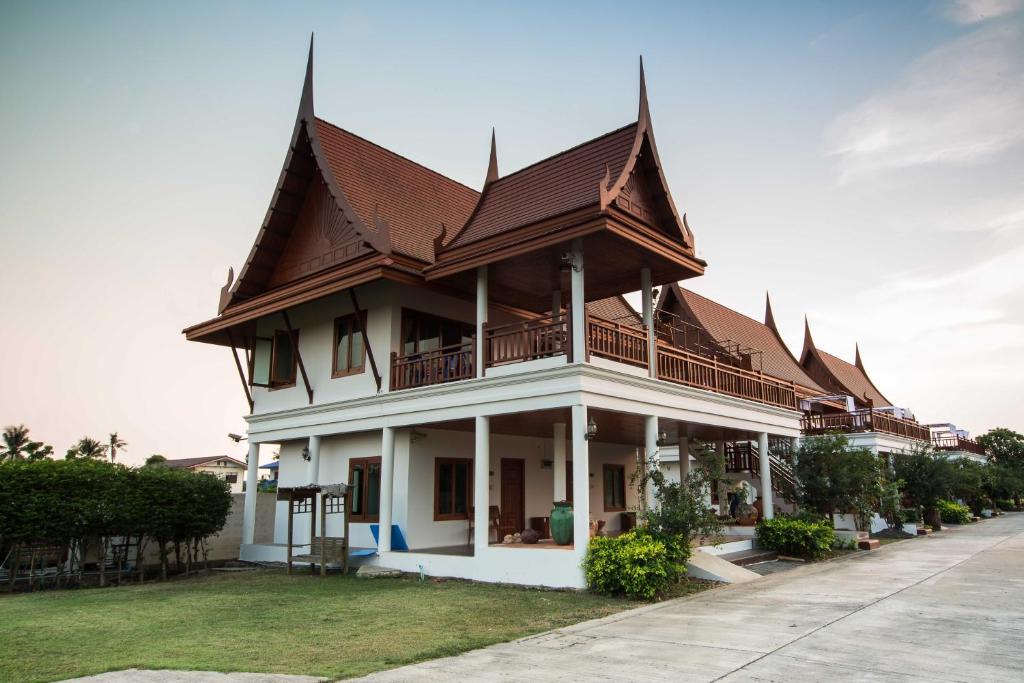 um grande edifício branco com um telhado castanho em Thaihome Resort em Ban Bang Muang