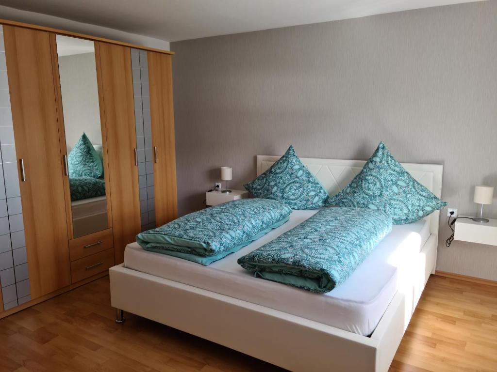 a bedroom with a bed with blue pillows on it at Ferienwohnung Pees in Baumholder