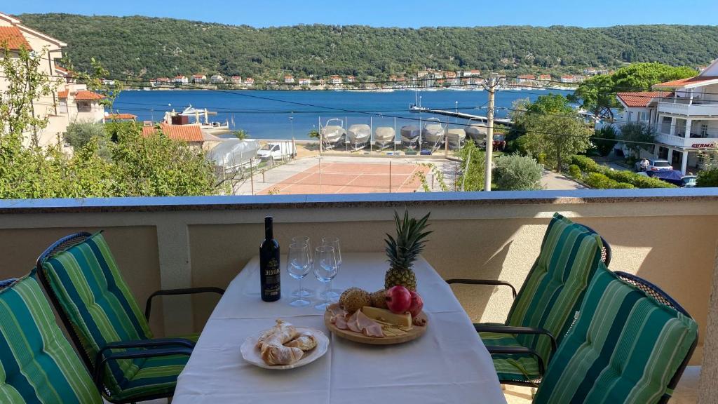 a table with a bottle of wine and a plate of food at Apartments Poljak in Supetarska Draga
