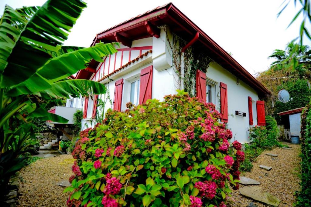 a house with red doors and flowers in front of it at Maison vue mer à GUETHARY 7 personnes in Bidart