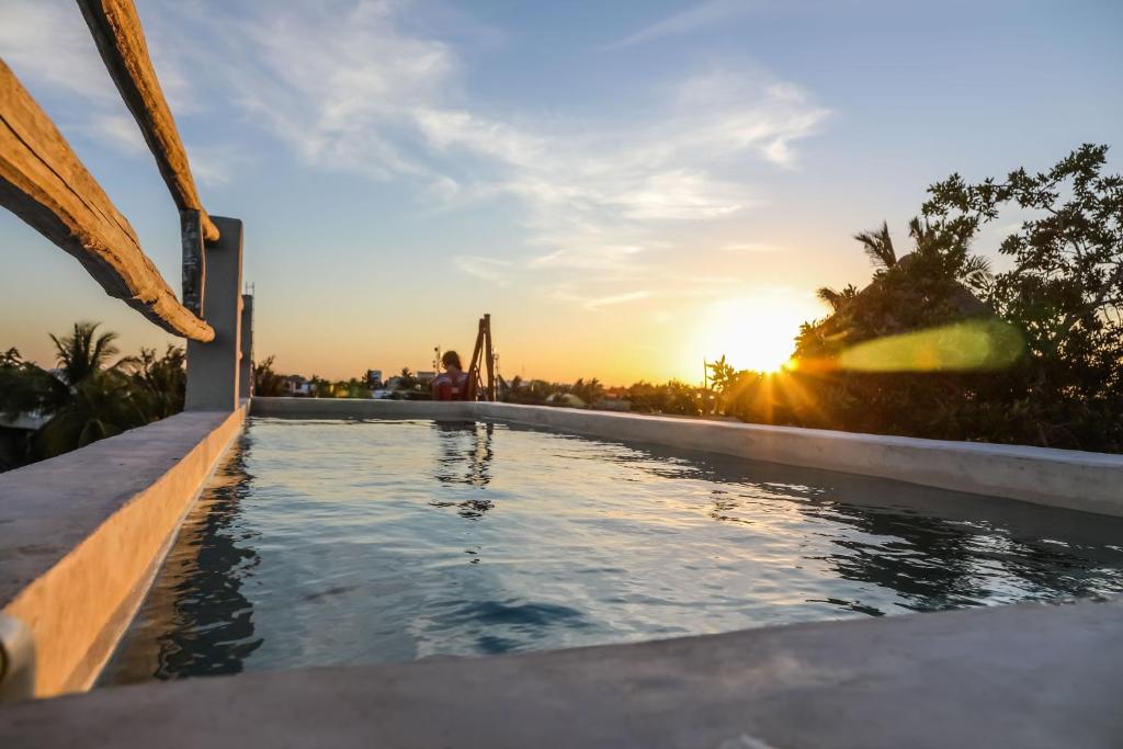 una piscina con puesta de sol en el fondo en La Casa de Mia Holbox, en Isla Holbox