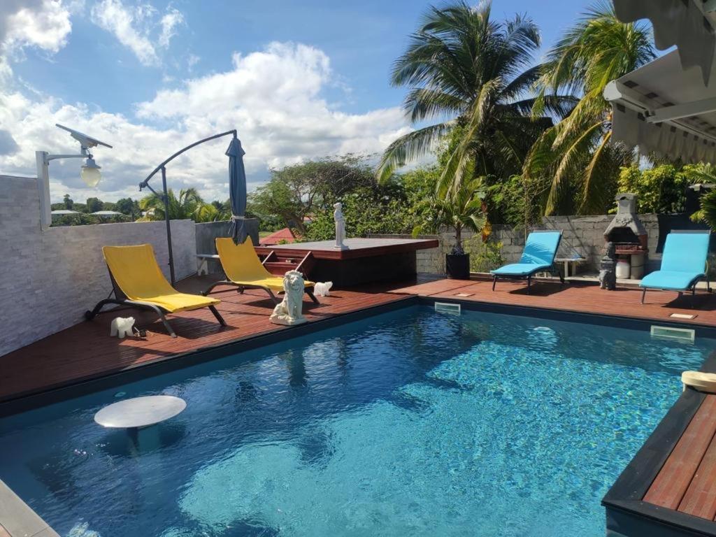 a swimming pool with two chairs and a table and a table and chairs at ZANNAMALAKA 2 F1 POUR UN GROUPE DE 4 Avec Piscine in Le Moule