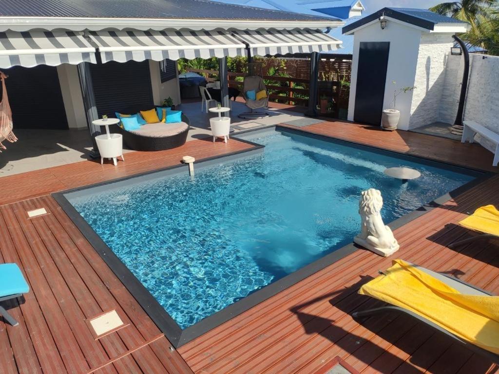 a swimming pool on a wooden deck with an umbrella at MALAKA F1 TOUT CONFORT Le Moule avec Piscine in Le Moule