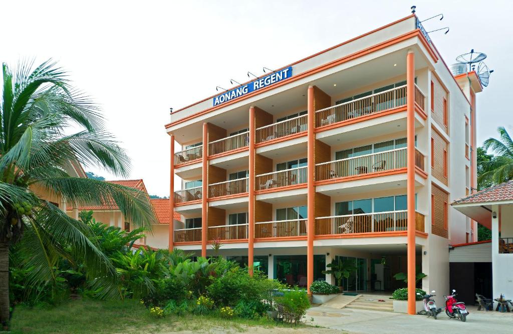 an orange hotel with a palm tree in front of it at Aonang Regent Hotel in Ao Nang Beach
