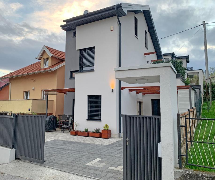 ein weißes Haus mit einem Tor und einem Zaun in der Unterkunft Apartment Maksimir Yard Zagreb in Zagreb