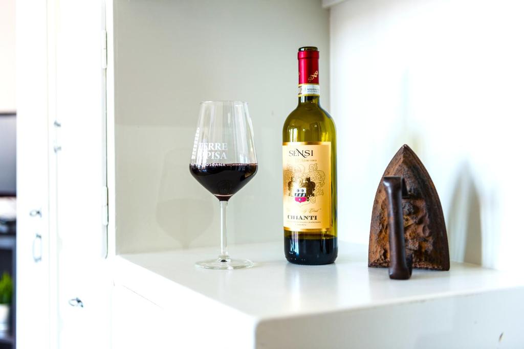 uma garrafa de vinho e um copo numa prateleira em Hostly - Family Home Cisanello em Pisa