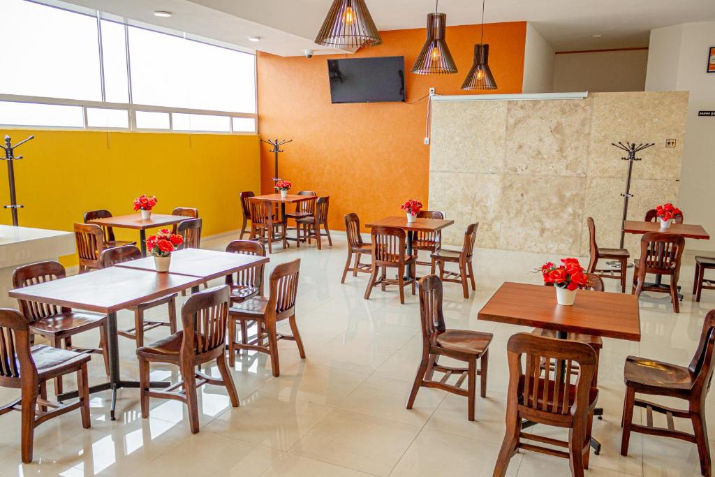 a restaurant with tables and chairs and a yellow wall at Hotel Klimt in Xalapa