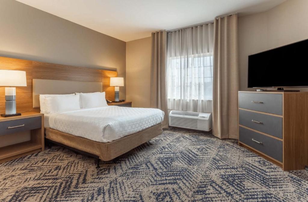 een hotelkamer met een bed en een flatscreen-tv bij Candlewood Suites Ofallon, Il - St. Louis Area by IHG in O'Fallon