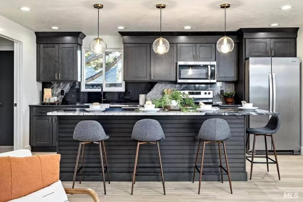 a kitchen with black cabinets and a kitchen island with stools at Mid Century Modern Boise-River Bungalow w/ Hot Tub in Boise