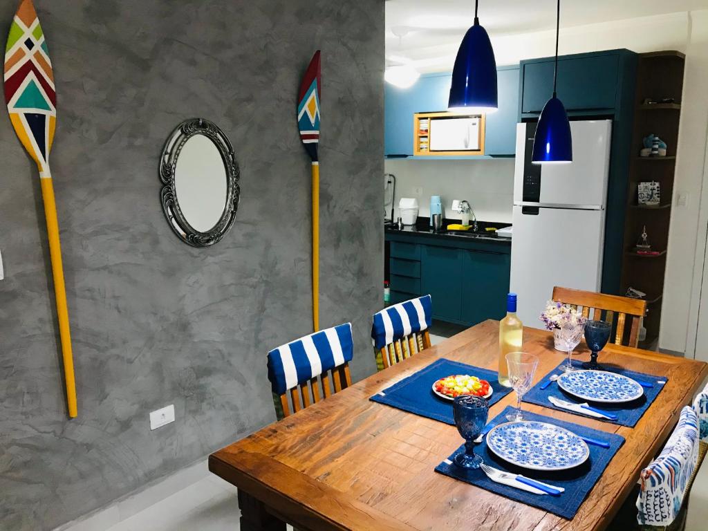 a dining room with a wooden table and a kitchen at Apt Familiar-Condomínio fechado UBATUBA in Ubatuba