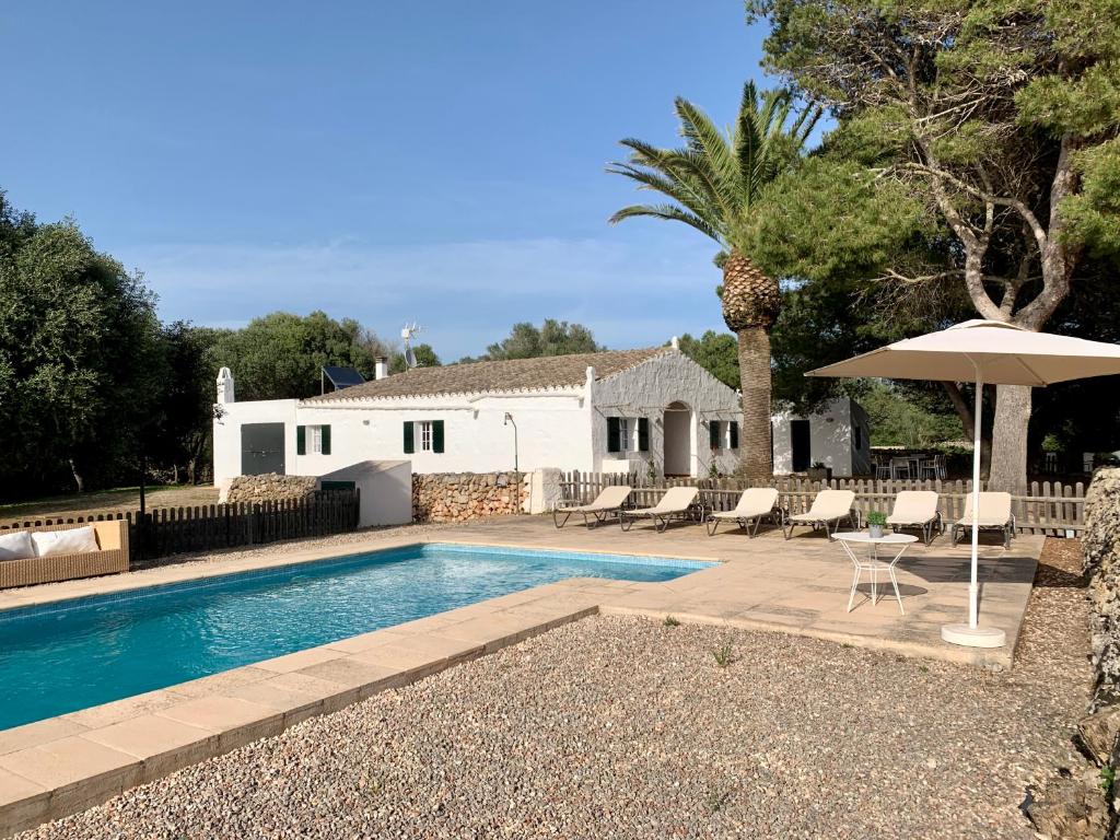 a swimming pool with an umbrella and a house at Islanders Menorca Country Club in Son Carrio