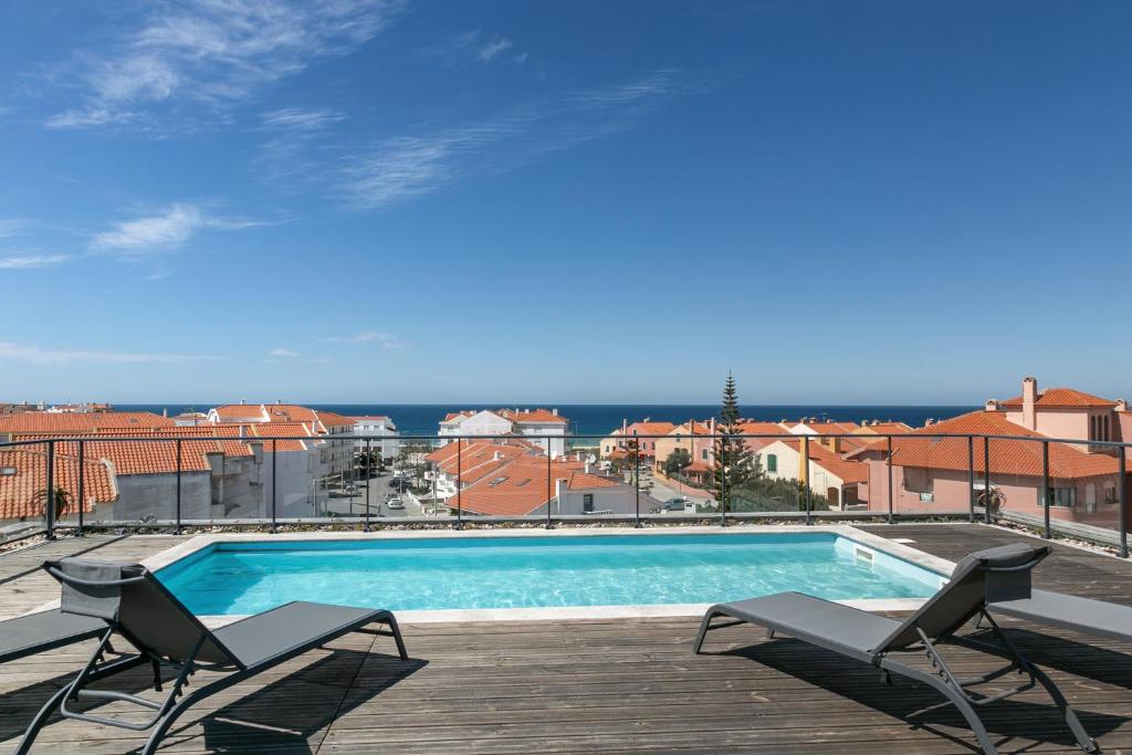 a swimming pool with two chairs on a deck at Consolação Supertubos Beach Apartment in Consolação