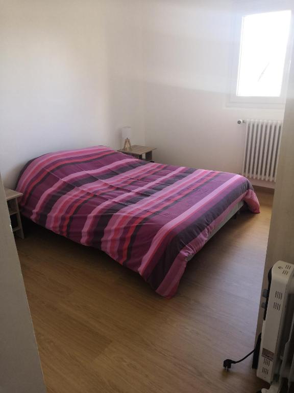 a bed in a room with a purple blanket on it at Logement neuf en face de la forêt. Accès cour. in Bagnoles de l&#39;Orne
