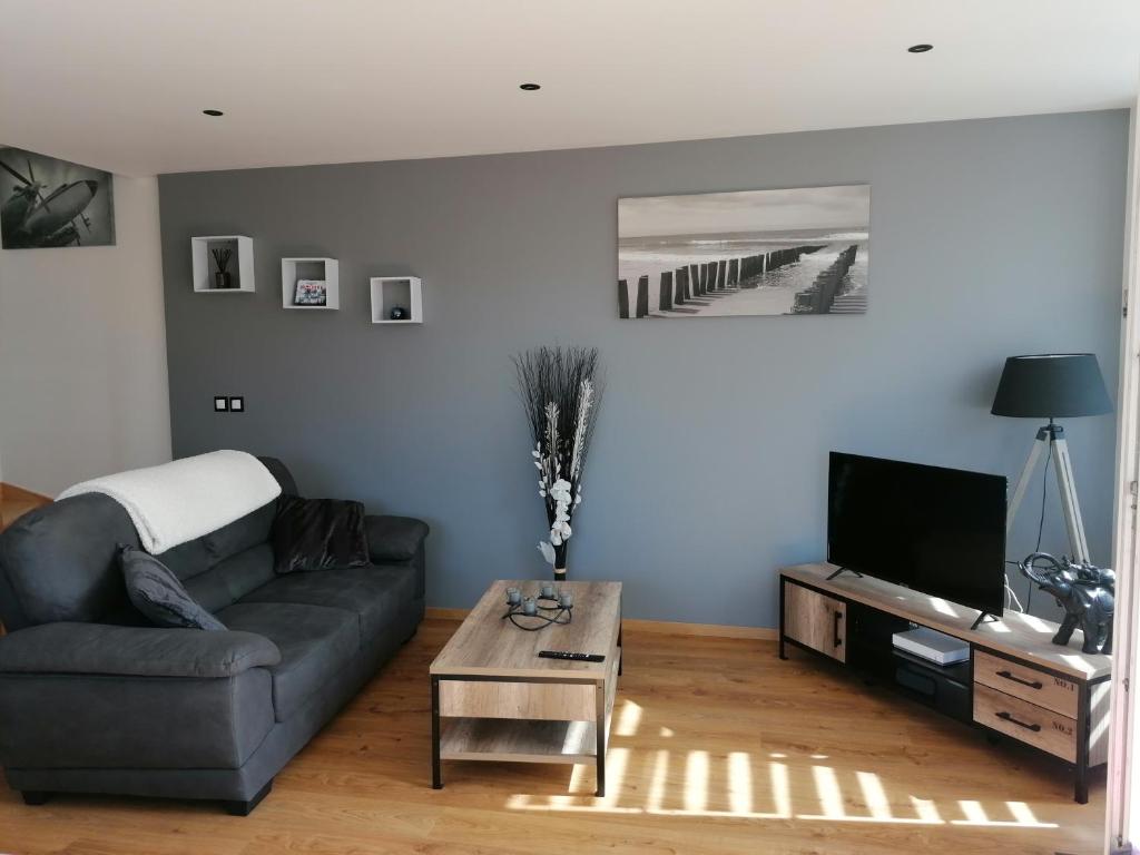 a living room with a couch and a tv at gite le C-47 in Sainte-Mère-Église