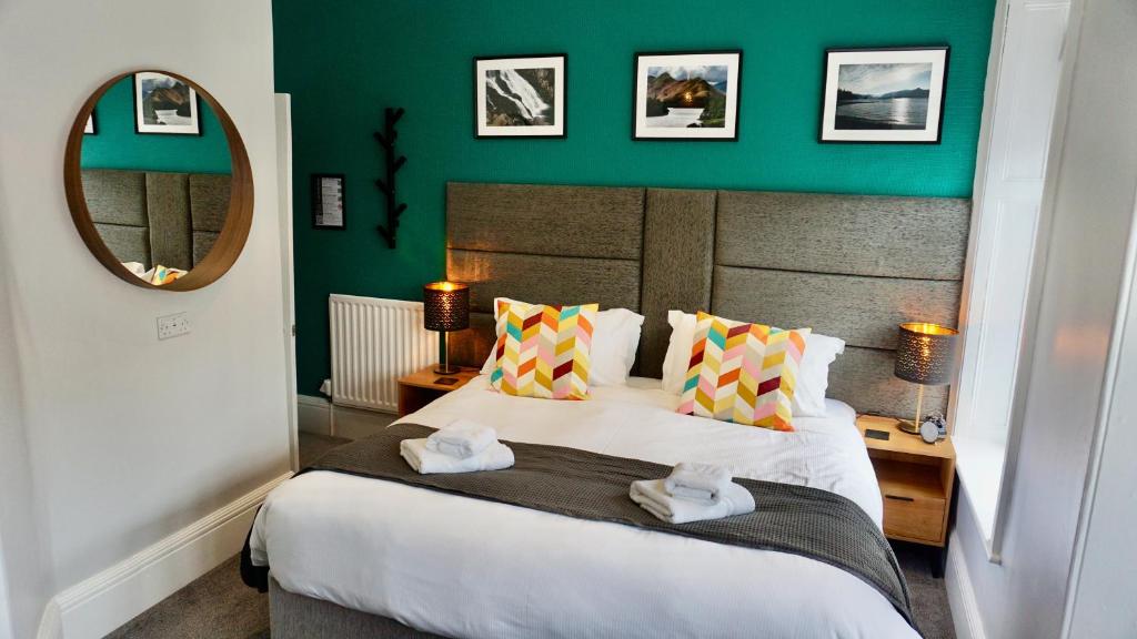 a bedroom with a large bed with a green wall at Greystoke House in Keswick