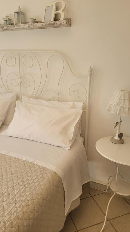 a bed with a white headboard and a table with a lamp at Domus Olea in Policastro Bussentino