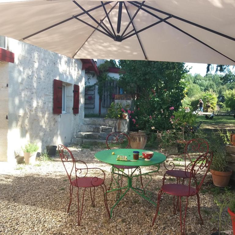 - une table et des chaises sous un parasol dans la cour dans l'établissement Maison 18eme siècle, à Le Moulinaud