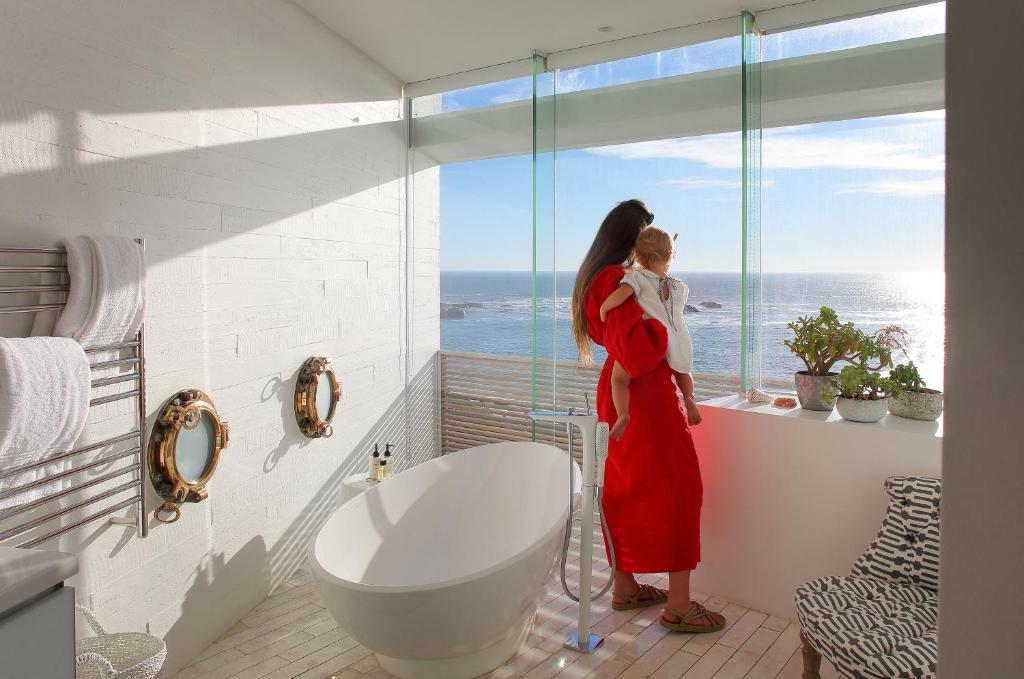 a woman standing in a bathroom looking out the window at Clifton Ezulwini in Cape Town