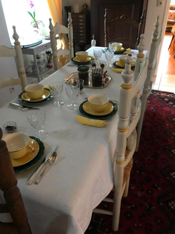 einen Tisch mit einem weißen Tischtuch mit Tellern und Gläsern in der Unterkunft L'Hirondelle in Saint-Jacut-les-Pins