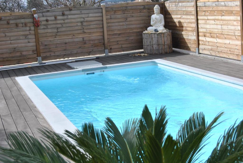 a swimming pool on a deck with a statue next to it at gîtes aux portes des Cévennes in Saint-Christol-lès-Alès