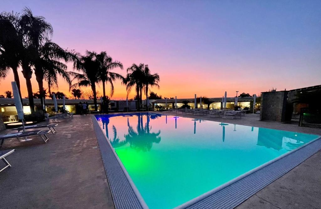 a large swimming pool with a sunset in the background at Egò Salento in Galatina