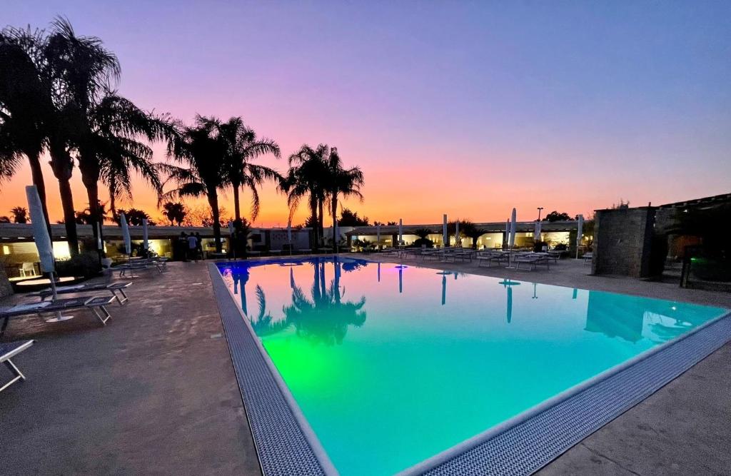 ein großer Pool mit Sonnenuntergang im Hintergrund in der Unterkunft Egò Salento in Galatina