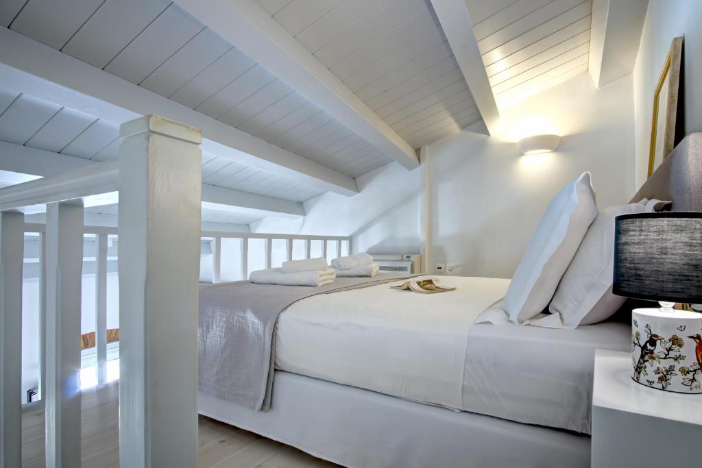una camera da letto bianca con un grande letto bianco e pareti bianche di Corfu Centro Storico flat a Città di Corfù