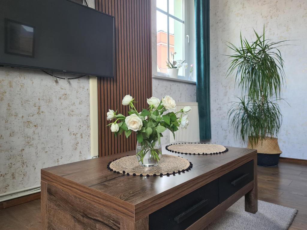 a vase of white flowers on a wooden table at Apartament w Rynku For You in Bolesławiec