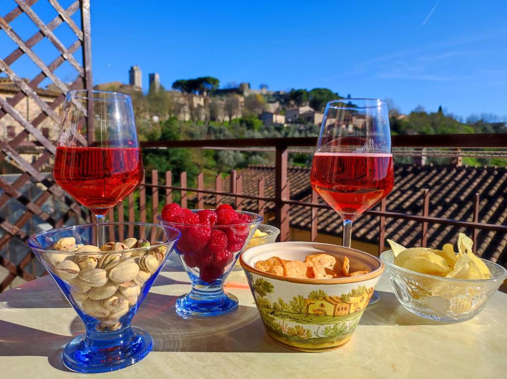 due bicchieri di vino e ciotole di cibo su un tavolo di Lovely Balcony San Gimignano Apartments a San Gimignano