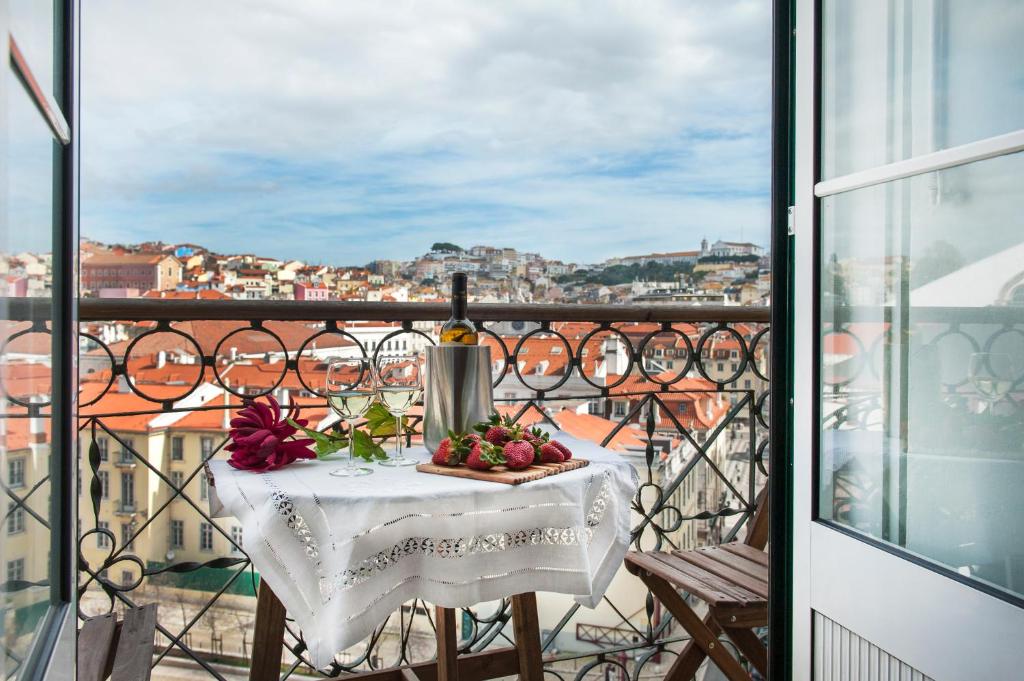 里斯本的住宿－羅西奧- 希亞多|里斯本奶酪和葡萄酒公寓式酒店，阳台上的桌子上摆放着一瓶葡萄酒和水果