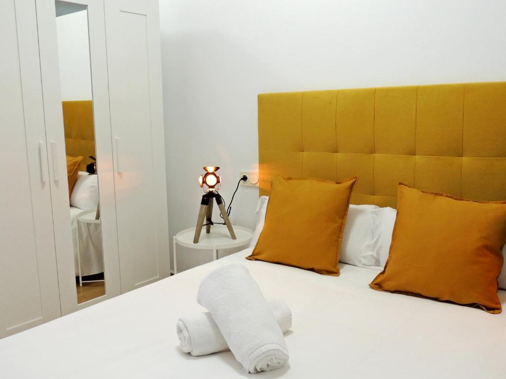 ein Schlafzimmer mit einem Bett mit gelben Kissen und einem Spiegel in der Unterkunft Casa Aurea-Apartamento zona antigua,parking y wifi by DeLabra Apartments in Oviedo