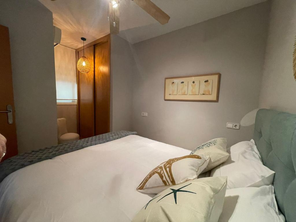 1 dormitorio con 1 cama con sábanas y almohadas blancas en Les Palmeres Centre, en Les Cases d'Alcanar