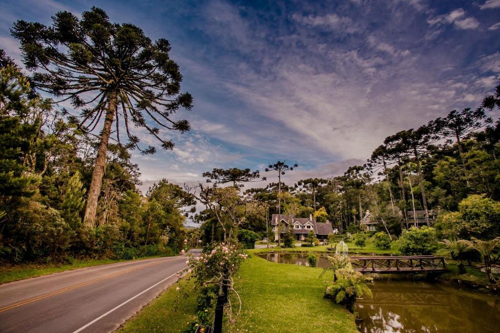 a road with a tree and a house and a bridge at Estalagem Coração Da Mata in Gramado