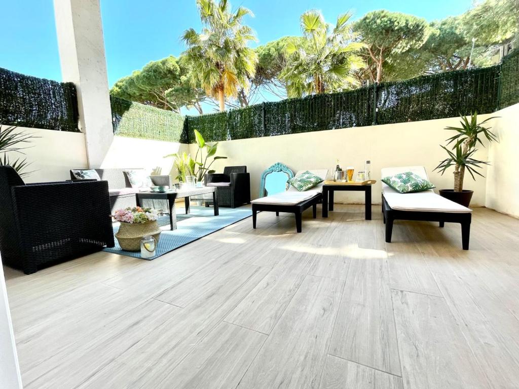 d'une terrasse avec des chaises, des tables et des palmiers. dans l'établissement Arena Castelldefels, à Castelldefels