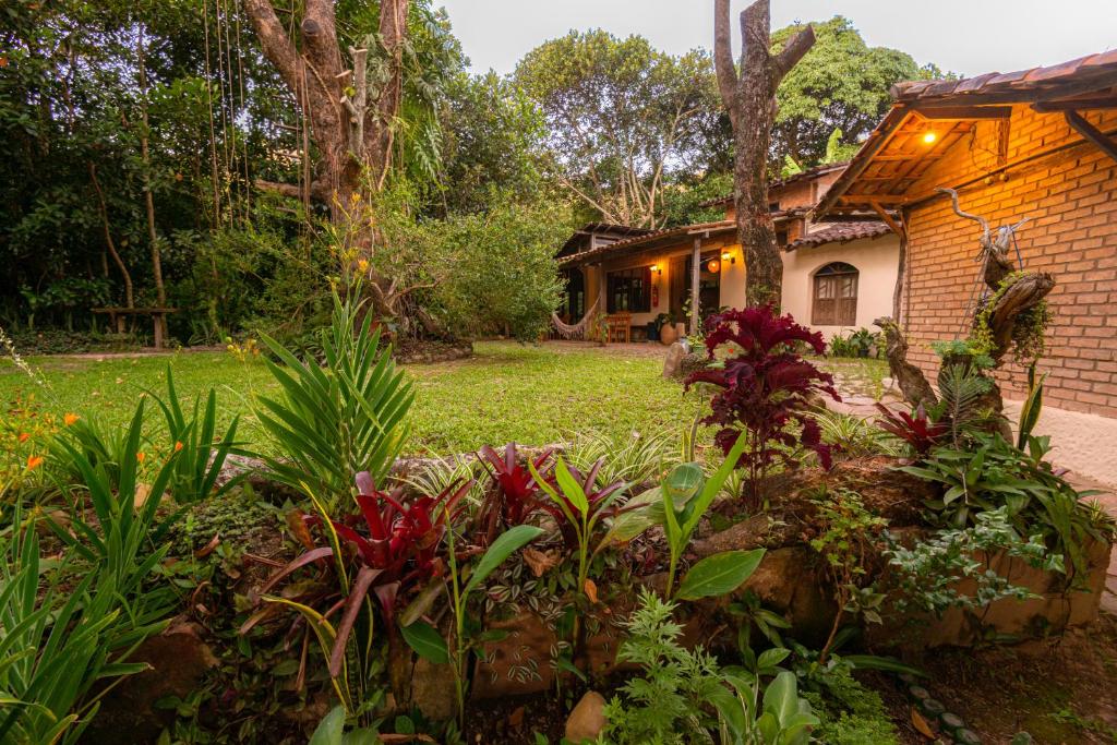 un jardín frente a una casa con flores en Dormitório - Hospedagem Caminho da Angélica, en Vale do Capao