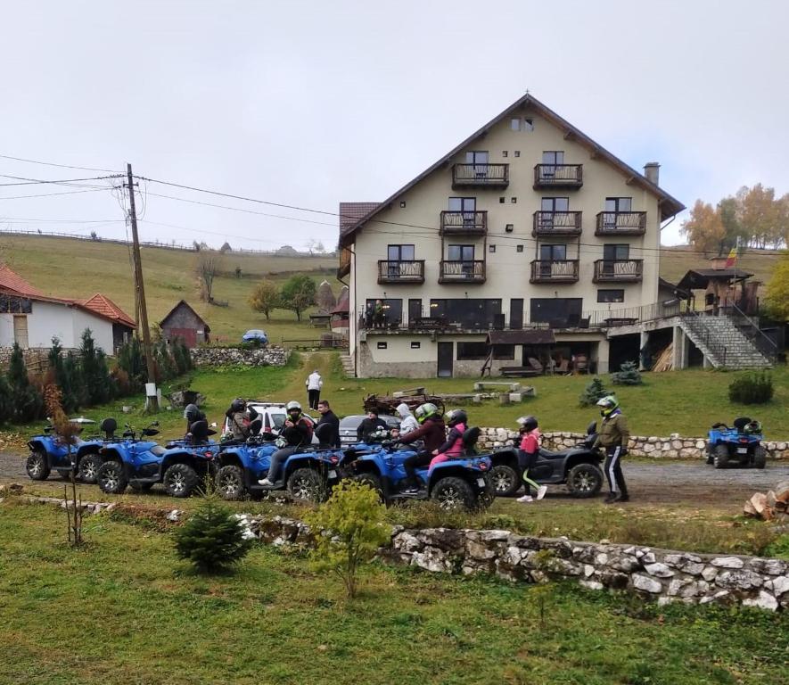 a group of people on atvs parked in front of a house at Pensiunea Ursul Carcotas in Fundata