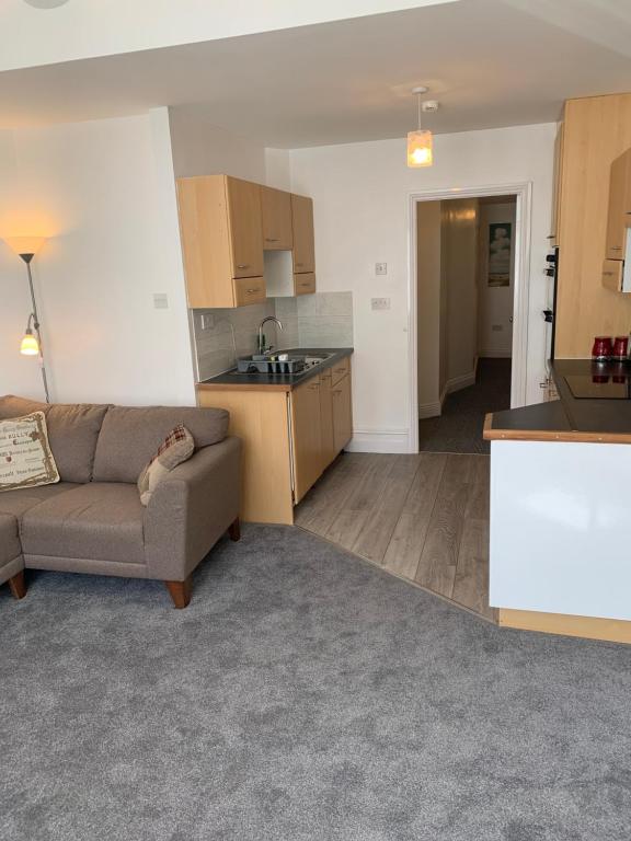 a living room with a couch and a kitchen at Delamere ground floor holiday flat in Blackpool