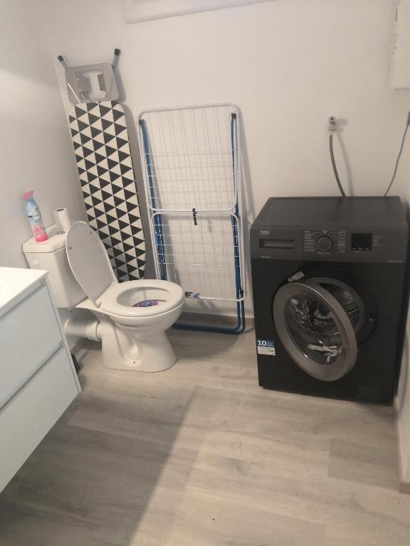 a bathroom with a washing machine and a toilet at Logement neuf en face de la forêt. Accès cour. in Bagnoles de l&#39;Orne