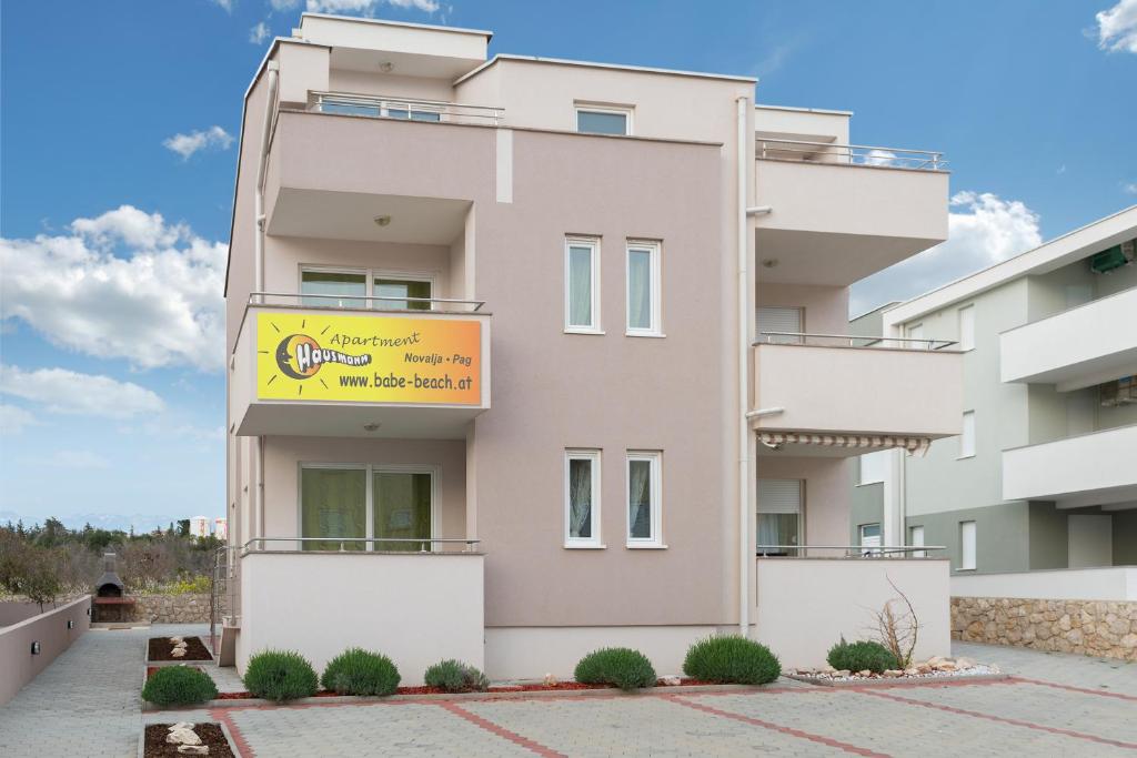 a building with a yellow sign in front of it at Apartments Hausmann in Novalja